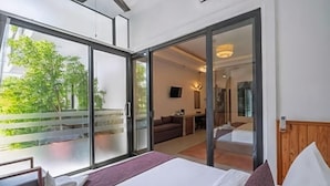 A hotel room with a bed, a desk, a chair, and a sliding glass door leading to a balcony. - The Tito Suite Residence (Siem Reap)
