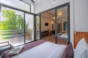 A hotel room with a bed, a desk, a chair, and a sliding glass door leading to a balcony.