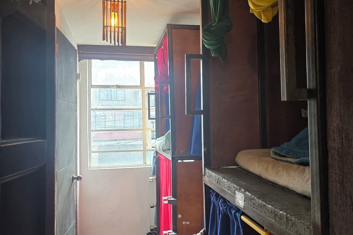 Een kleine kamer met stapelbedden, een klein raam en een vloer met een patroon.