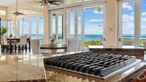 A kitchen with a gas stove, large windows, and a view of the ocean.