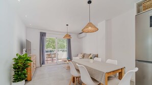Un comedor moderno con una mesa de madera, sillas blancas y lámparas colgantes de fibra.