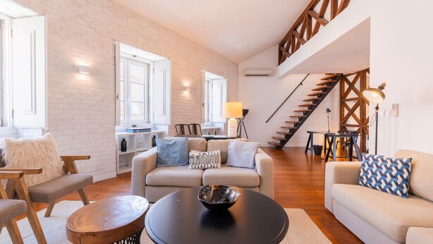 A spacious living area with a sofa, coffee table, and a staircase with wooden railings.