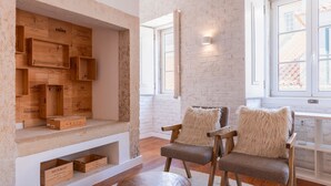 A cozy seating area with wooden crates and chairs, a brick wall, and large windows.