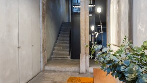 A narrow hallway with a staircase leading to a higher floor. A wooden bench is placed against the wall on the right side.