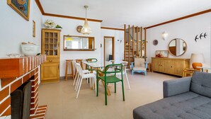 Een ruime woonkamer met een eettafel, stoelen, een bank en een open haard.