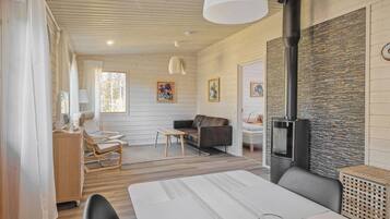 Una sala de estar acogedora con chimenea, paredes de madera y un comedor con mesa y sillas.