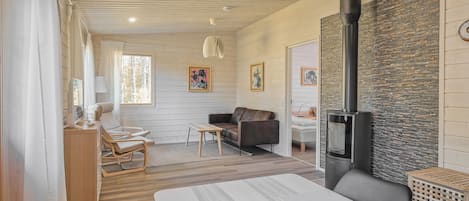 A cozy living room with a fireplace, wooden walls, and a dining area with a table and chairs.