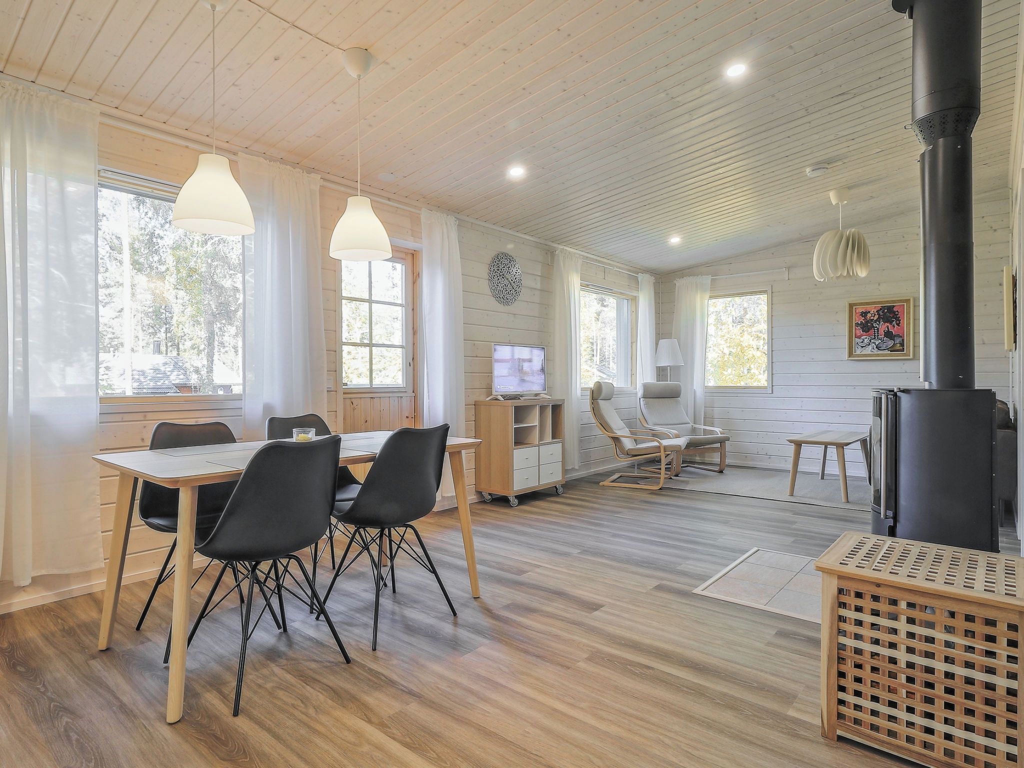 Una habitación amplia con suelo de madera, una mesa de comedor con sillas, un televisor y una chimenea.