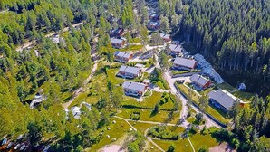 Luchtbeeld van een woongebied met meerdere huizen, omringd door dicht bos.