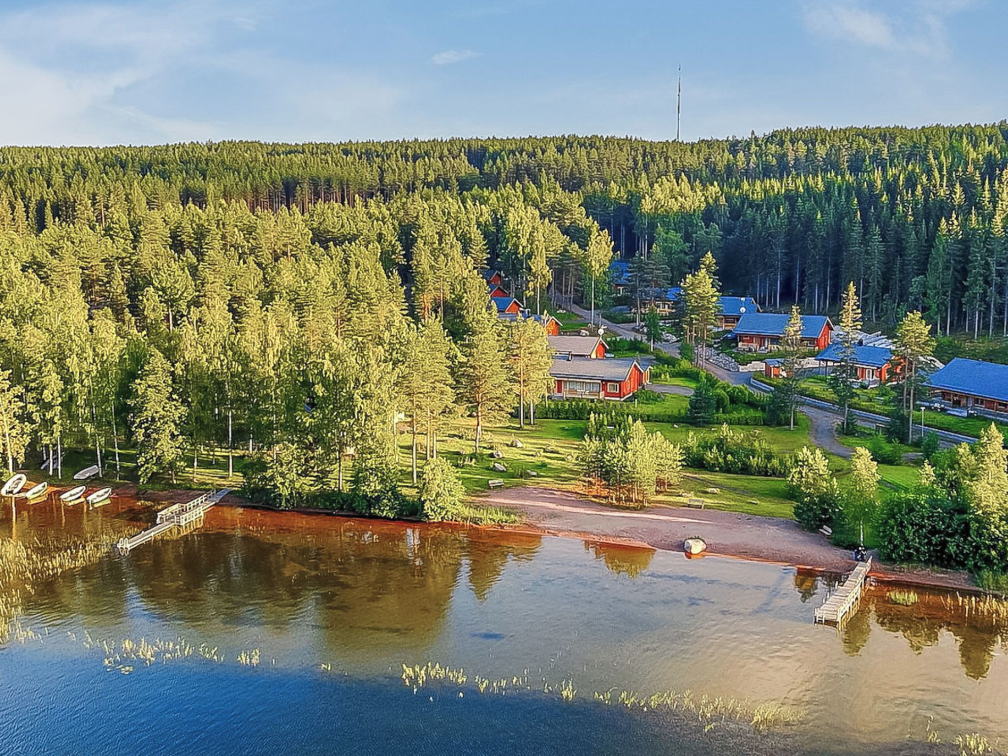 A lakeside property with cabins, a dock, and a forested backdrop.
