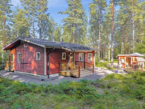 A cabin with a porch, surrounded by a forest.