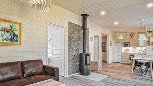 Een moderne woonkamer met een bruine leren bank, een houten salontafel, een stenen muur en een zwarte houtkachel.