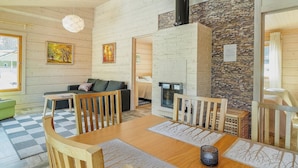 Een gezellige woonkamer met een open haard, houten wanden en een geruit vloertje.