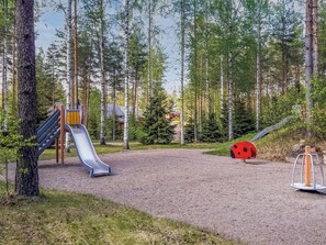 Un terrain de jeux avec un toboggan et une sculpture représentant une coccinelle.