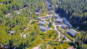 Luchtbeeld van een woongebied met meerdere huizen, omringd door dicht bos.