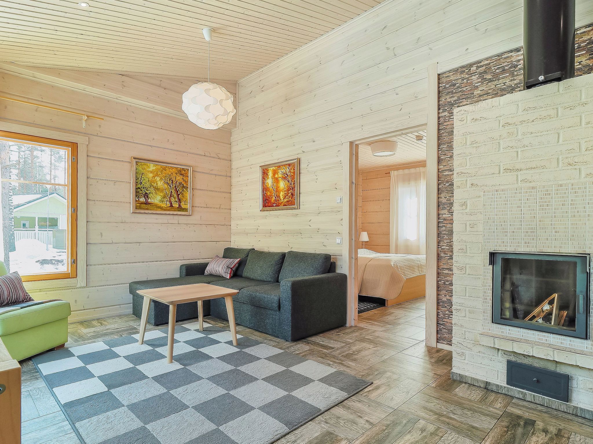A modern living room with a fireplace, a checkered rug, a sofa, and two paintings on the wall.
