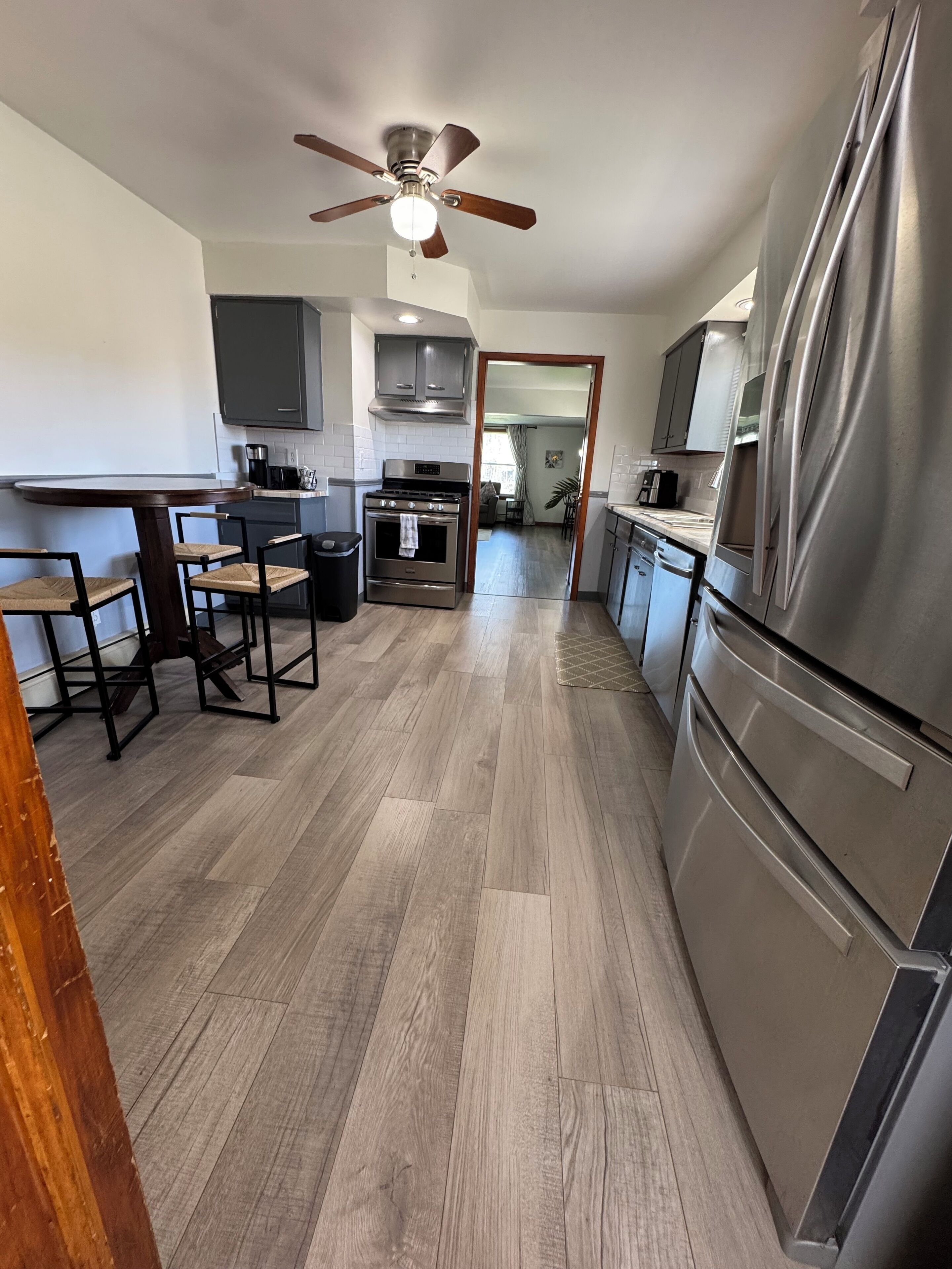 A modern kitchen with a central island, stainless steel appliances, and a ceiling fan.