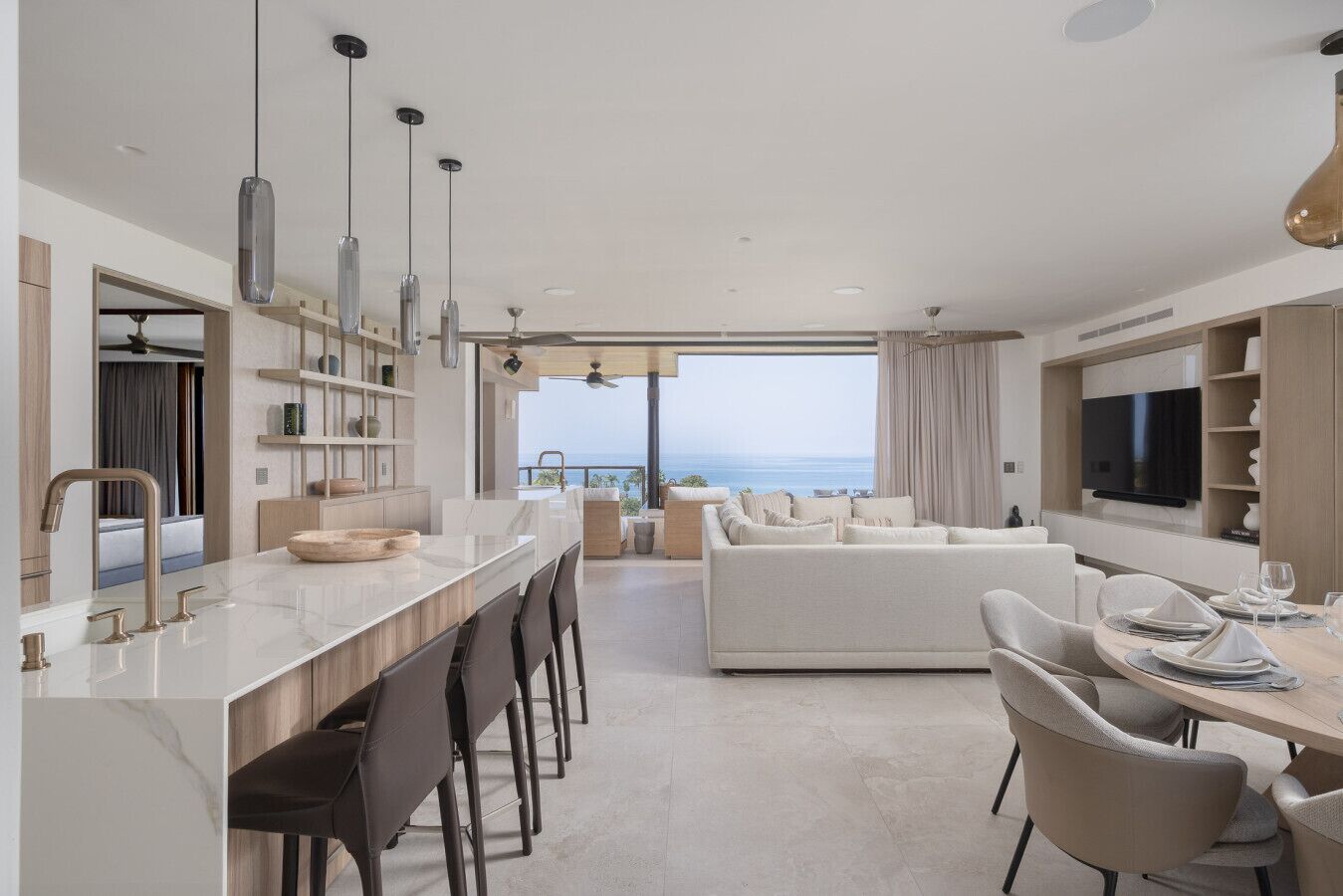 Una cucina moderna con isola centrale, sedute a bancone e zona pranzo con vista.