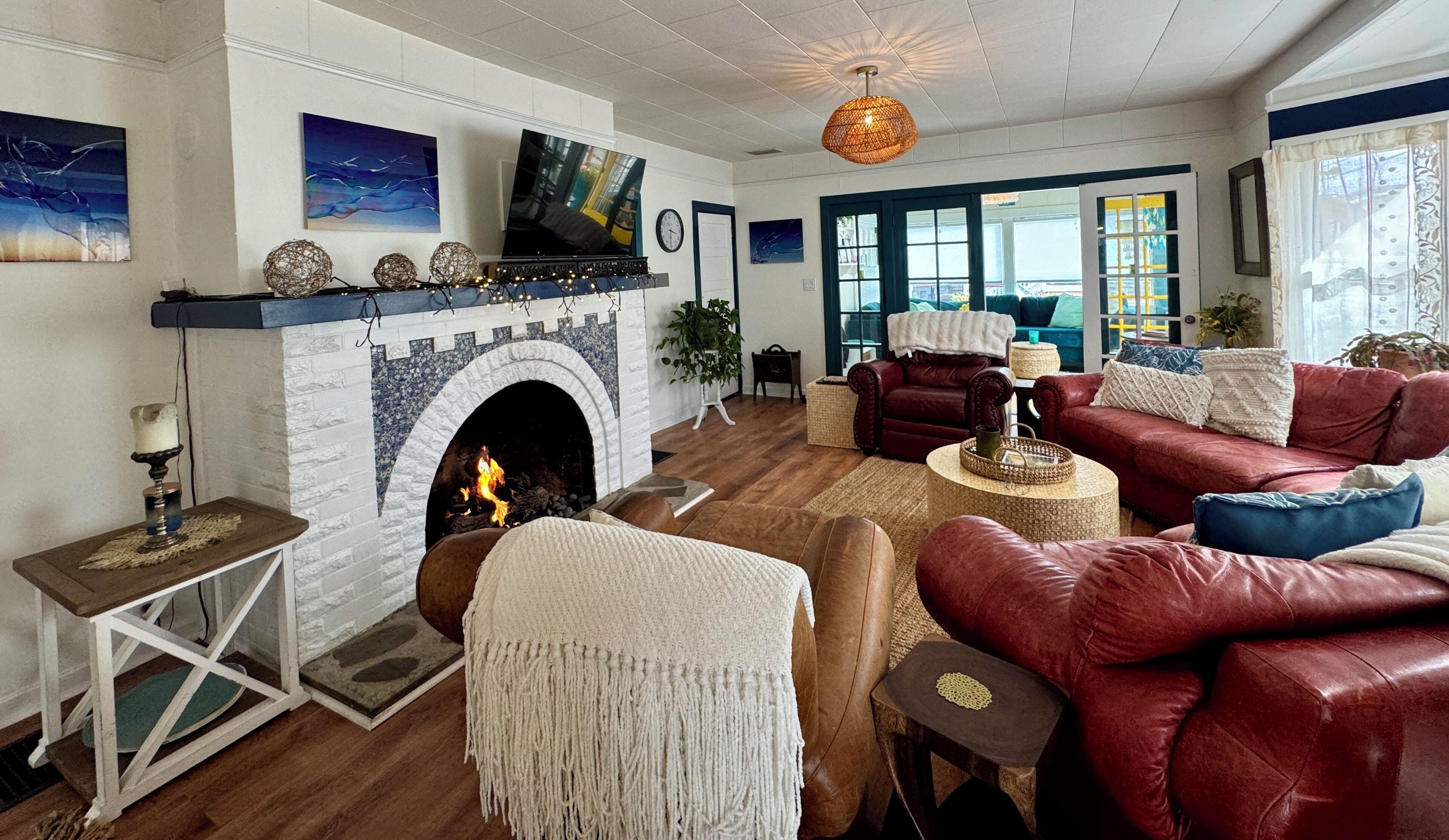 A living room with a fireplace, leather sofas, a television, and a large window.