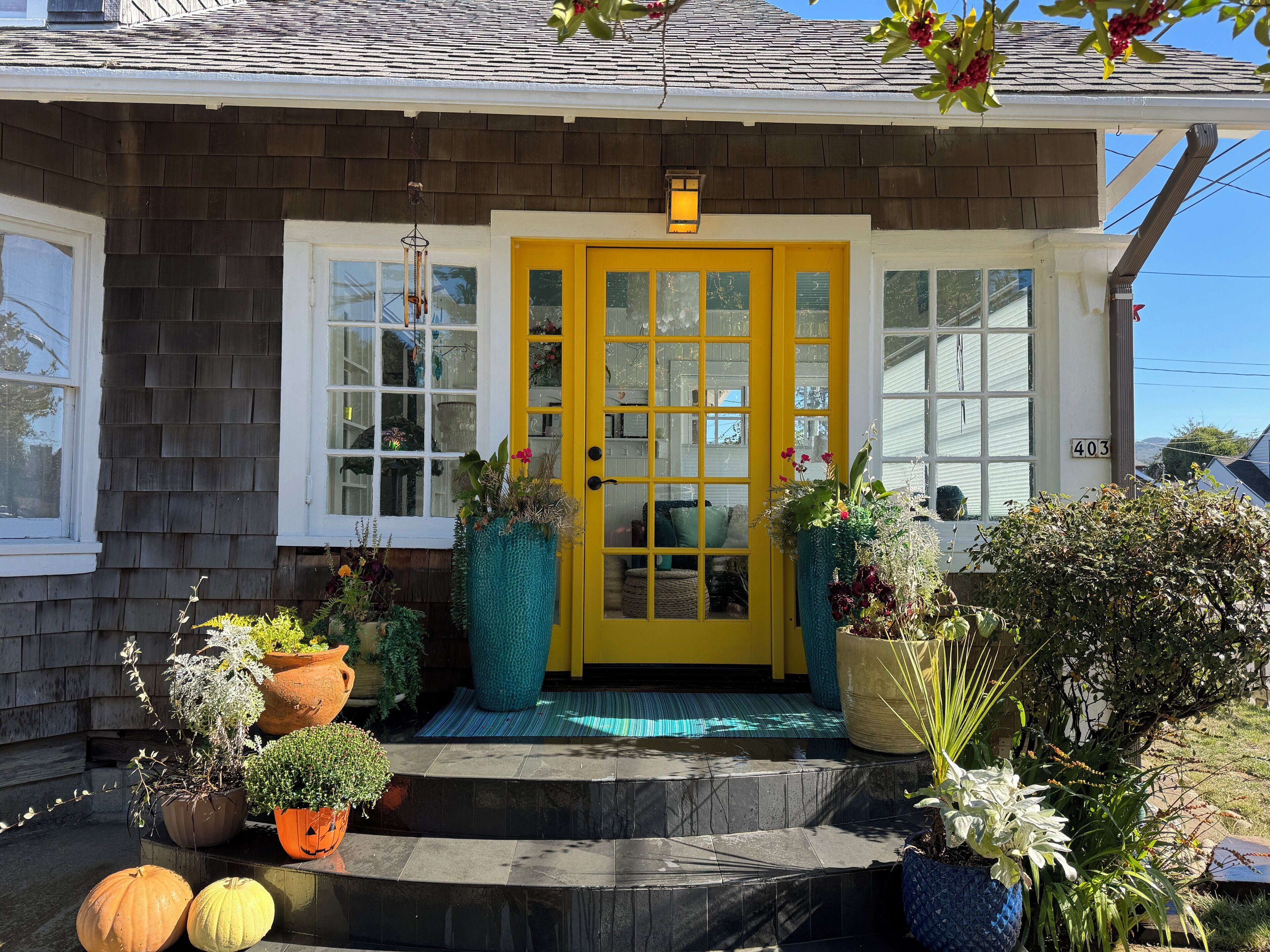 A house with a yellow front door, a mailbox, and a number 403 on the wall.