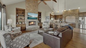 Un espacio habitable amplio con chimenea, un sofá, una mesa de centro y una cocina al fondo.