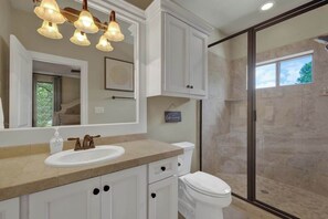 A bathroom with a beige countertop, white cabinets, a white sink, and a toilet. There is a large mirror above the sink and a shower with a glass door. - Canyon Lakehouse Panoramic Lake Views With Firepit! (Canyon Lake)