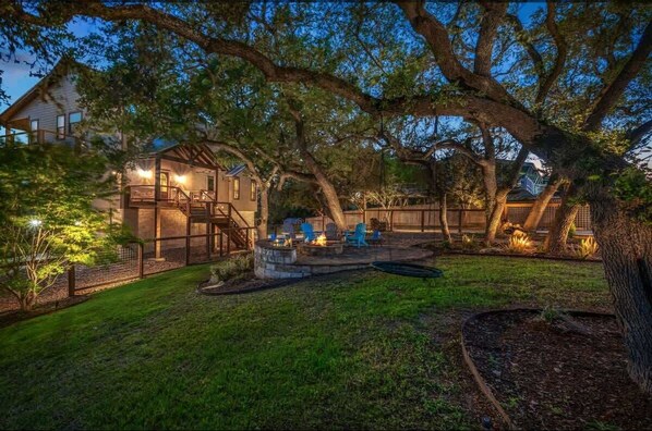 A backyard with a fire pit, outdoor seating, and a covered patio area.