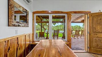 A wooden dining table with a view of outdoor seating and a wooden door.