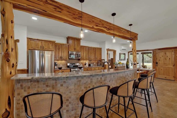 Una cocina con armarios de madera, una isla central con taburetes de bar e iluminación colgante.