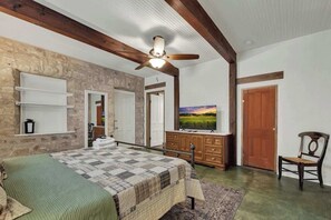 A bedroom with a bed, a dresser, a television, and a ceiling fan.