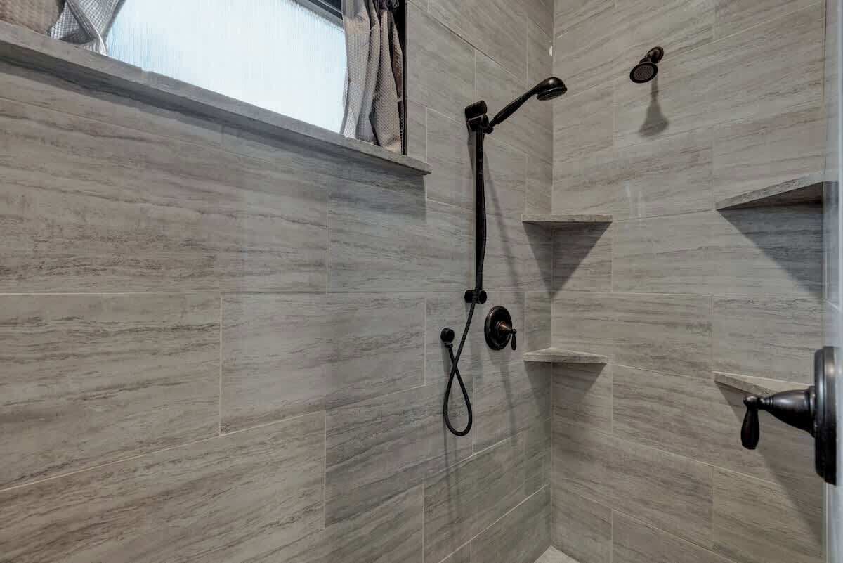 Un espace douche équipé d’un pommeau de douche à main et d’un robinet fixé au mur.