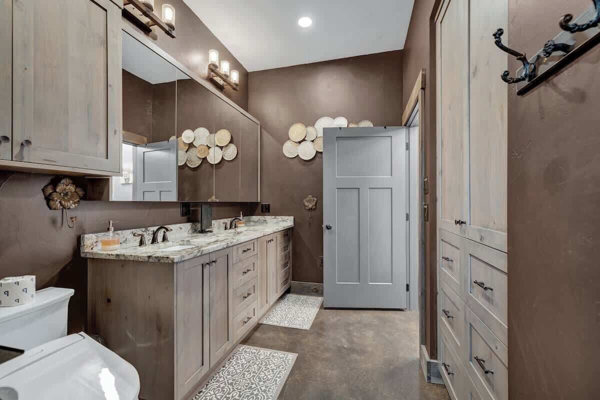 A modern bathroom with a marble vanity, a large mirror, and a door leading to another room.