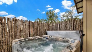 A hot tub with a wooden fence in the background. - West End Nest With Hot Tub! (Fredericksburg)