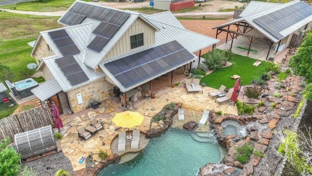 Ein Haus mit Swimmingpool, Solaranlage und Sitzgelegenheit im Freien.