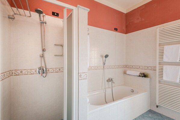Une salle de bain avec une douche, une baignoire et un porte-serviettes.