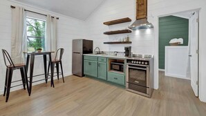 A kitchen with wooden cabinets, a stove, and a sink. - Cates Cottage in the Hill Country 8 Mins to Fred! (Fredericksburg)