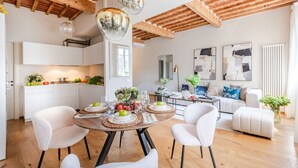 Une cuisine moderne avec des meubles blancs, un coin repas doté d’une table ronde et un salon avec un canapé et des œuvres d’art abstraites.