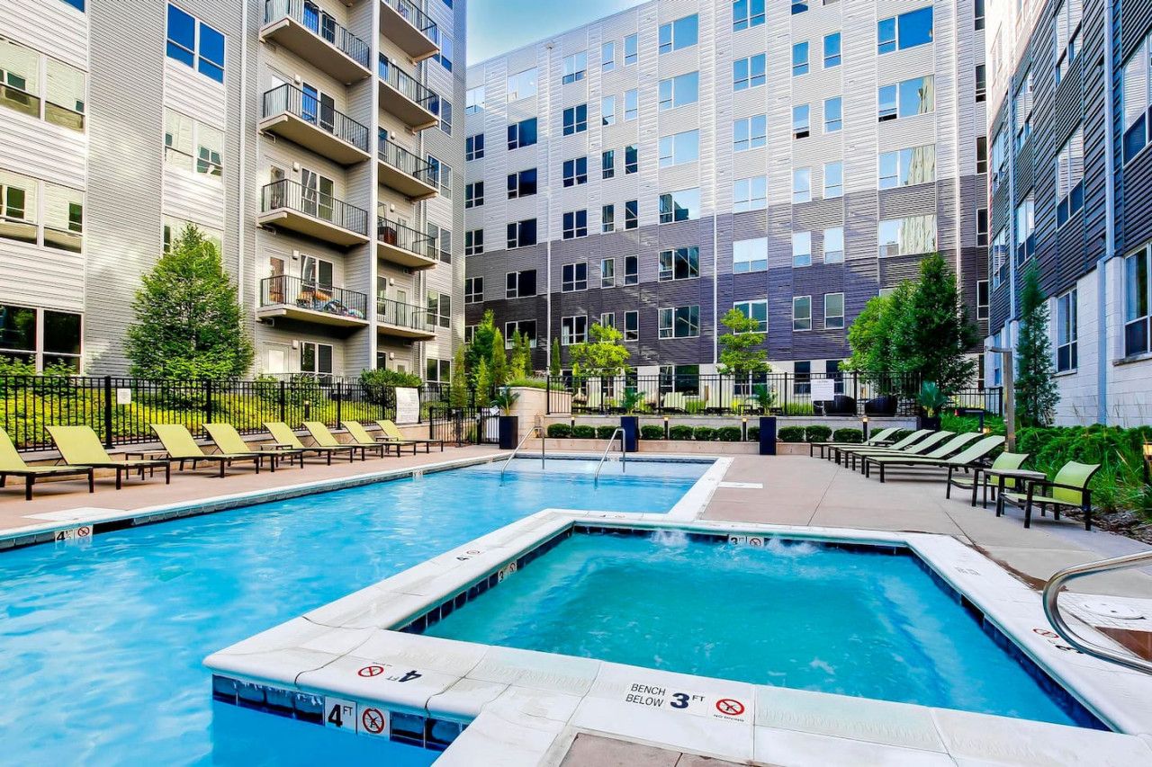 A swimming pool with lounge chairs and a multi-story building with balconies.