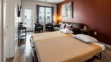 A bedroom with a double bed, a sofa, a TV, and a window with curtains.