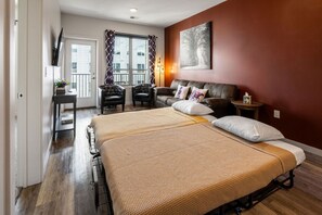 Un dormitorio con una cama doble, un sofá, un televisor y una ventana con cortinas.