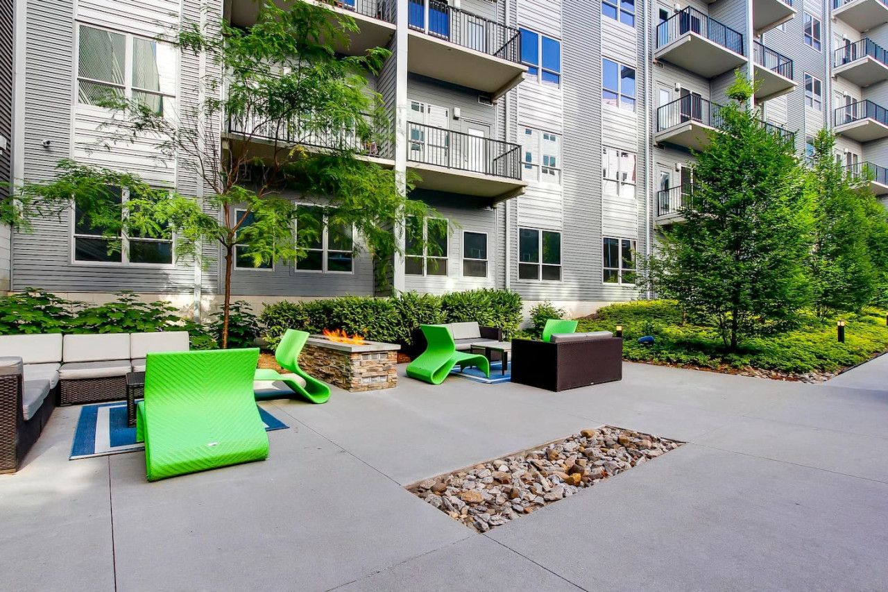 An outdoor seating area with modern furniture, a fire pit, and a landscaped garden.