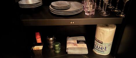 Un comptoir de cuisine avec une pile d’assiettes, des verres et un rouleau d’essuie-tout.