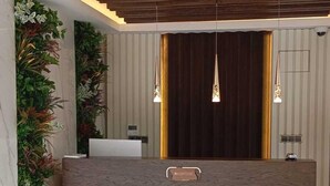 A reception desk with a wooden top, a marble base, and a vertical plant wall to the left. - Ladur Resort Hotel (Maçka)