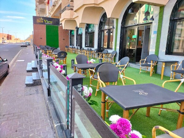 An outdoor seating area with tables and chairs, a green awning, and a sign for 'Sea View'. - Sea View Hotel (Hurghada)
