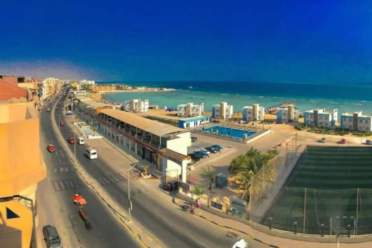 A coastal urban area with a road, buildings, and a beach.