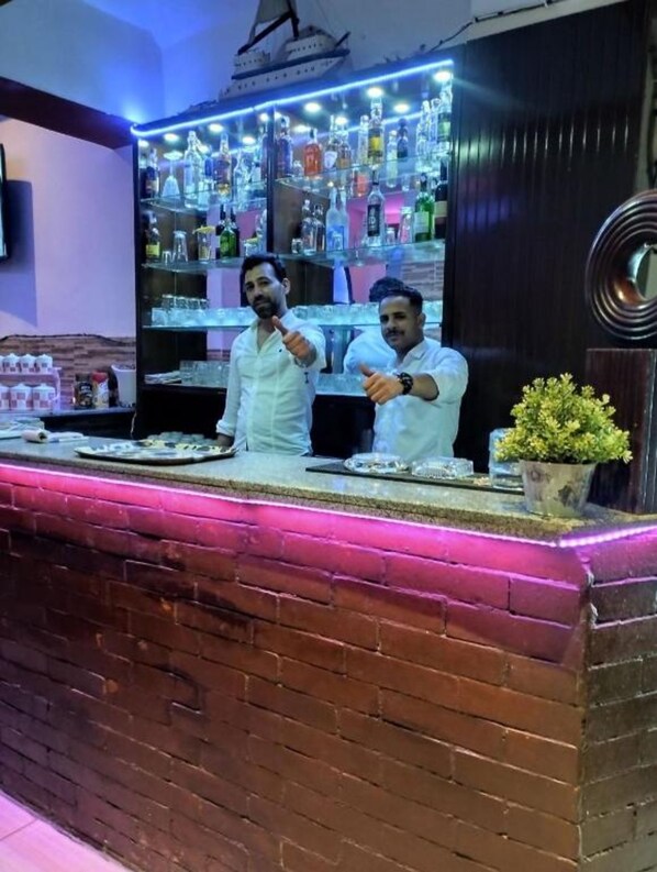 A bar area with two bartenders, a variety of bottles, and a decorative sail on the ceiling. - Sea View Hotel (Hurghada)