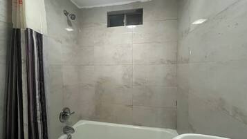 A bathroom with a bathtub, a shower, and a window.
