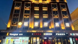 A multi-story building with illuminated signage, storefronts, and a clear view of the entrance.