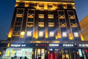 A multi-story building with illuminated signage, storefronts, and a clear view of the entrance.