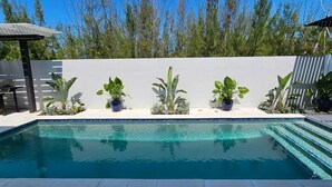 A swimming pool with potted plants and a pergola.